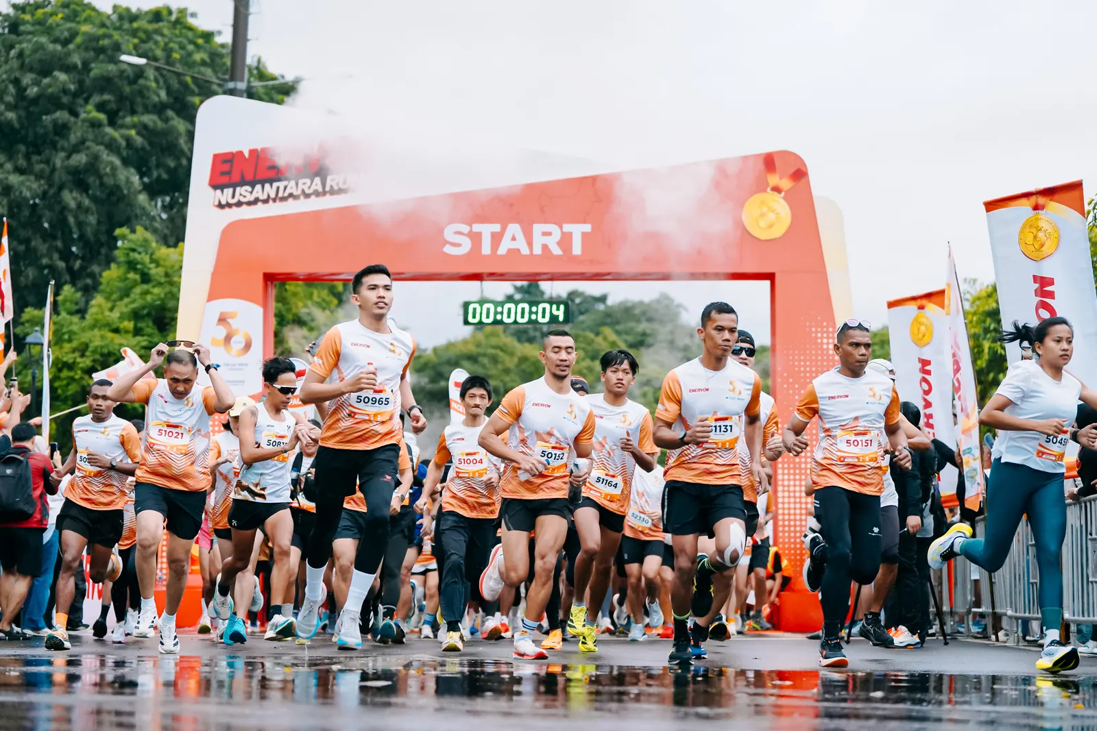 Pelari melintasi garis start Enervon Nusantara Run 2026 saat hujan